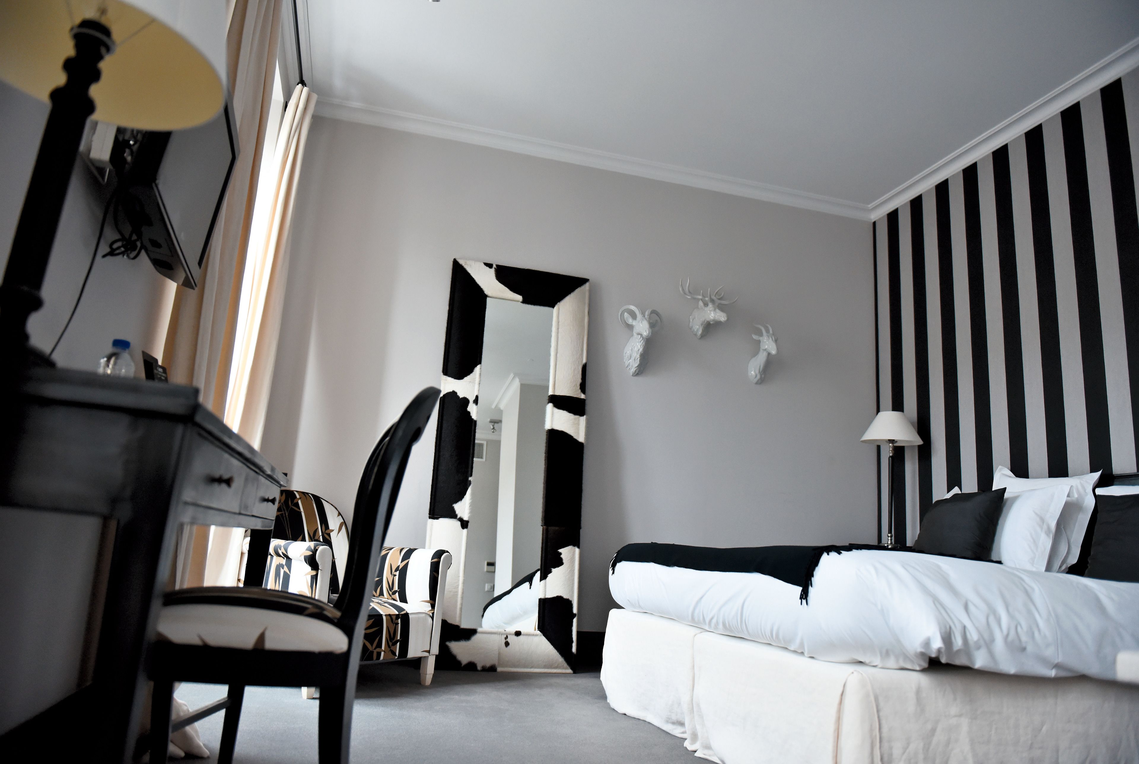 A modern bedroom with a bed, a chair, a desk, and a mirror.