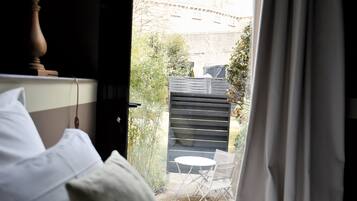 Habitación de hotel con cama, almohadas, una lámpara y vistas a un espacio exterior con mesa y sillas.