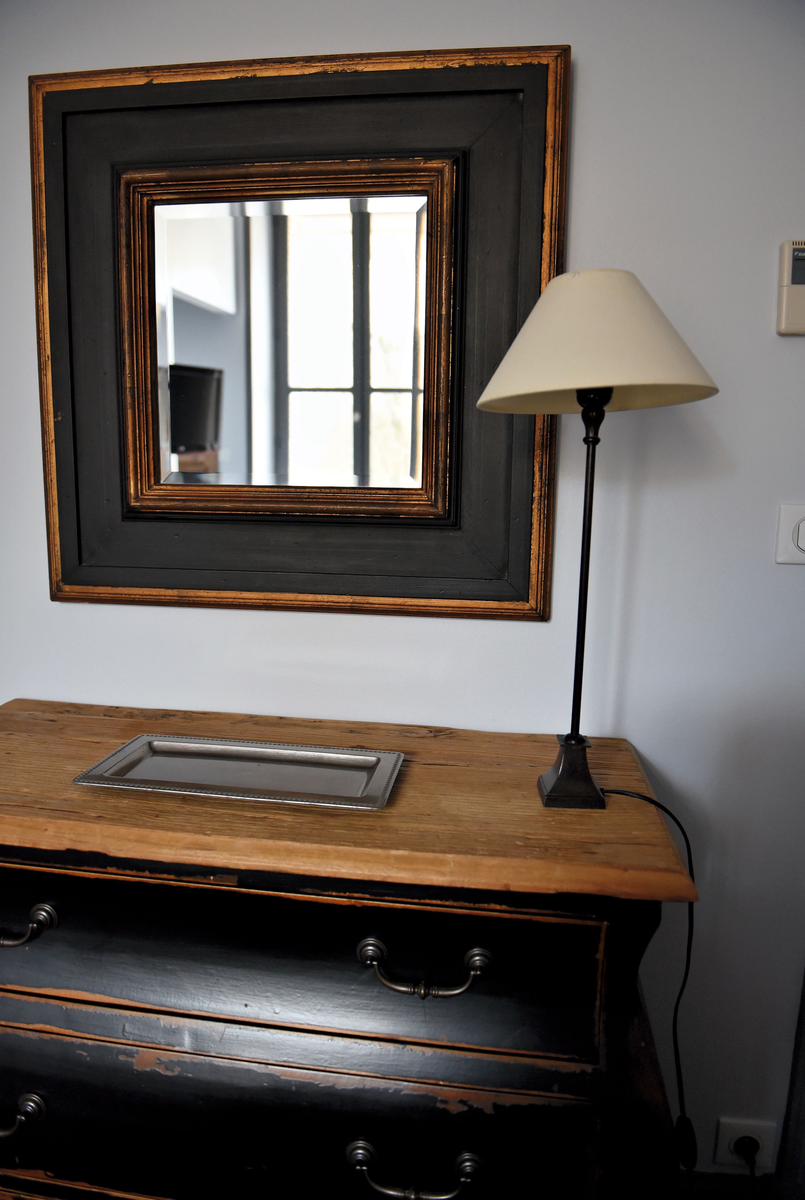 Une commode en bois avec un miroir et une lampe.