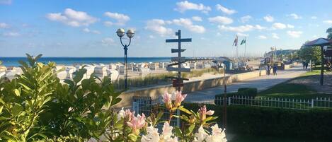 A coastal promenade with a street lamp, a signpost, and a flower-lined path.