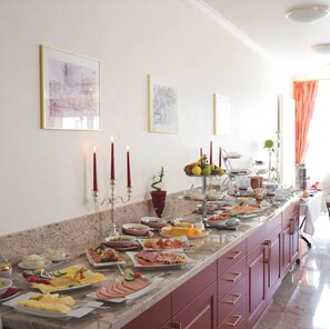 A buffet setup with various food items and a candelabra with candles.