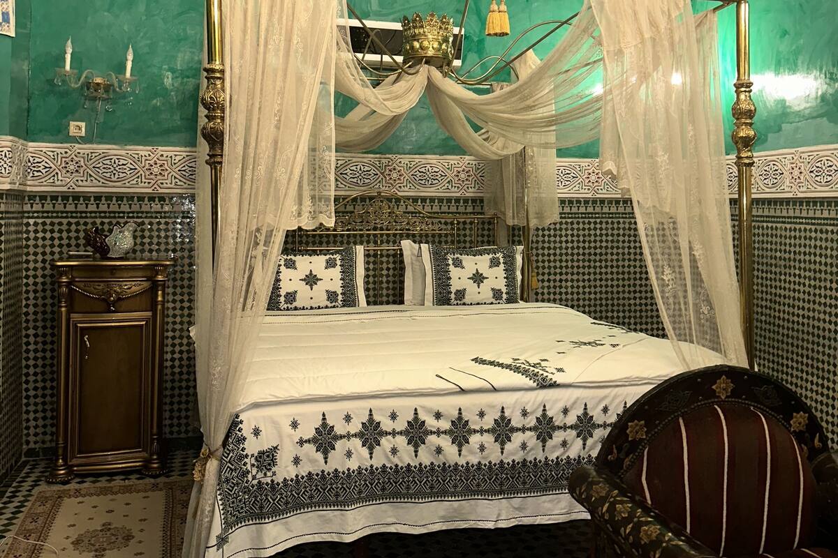 Une chambre avec un lit à baldaquin, un lustre et un sol à motifs.