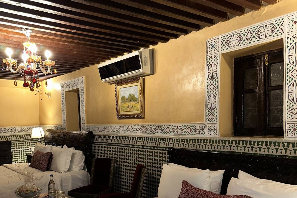 Une chambre d’hôtel avec un grand lit, une table de chevet avec une lampe, une chaise et un miroir décoratif.