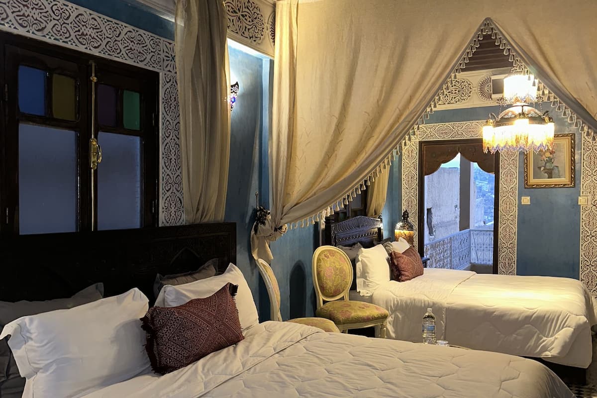 Une chambre avec deux lits, une chaise et un plafond décoratif.