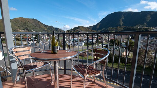 A balcony with a round table and two chairs, overlooking a street and mountains. - Broadway Motel (Picton)