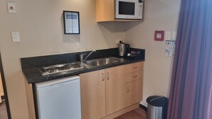 A compact kitchen with a microwave, sink, and a small refrigerator. - Broadway Motel (Picton)