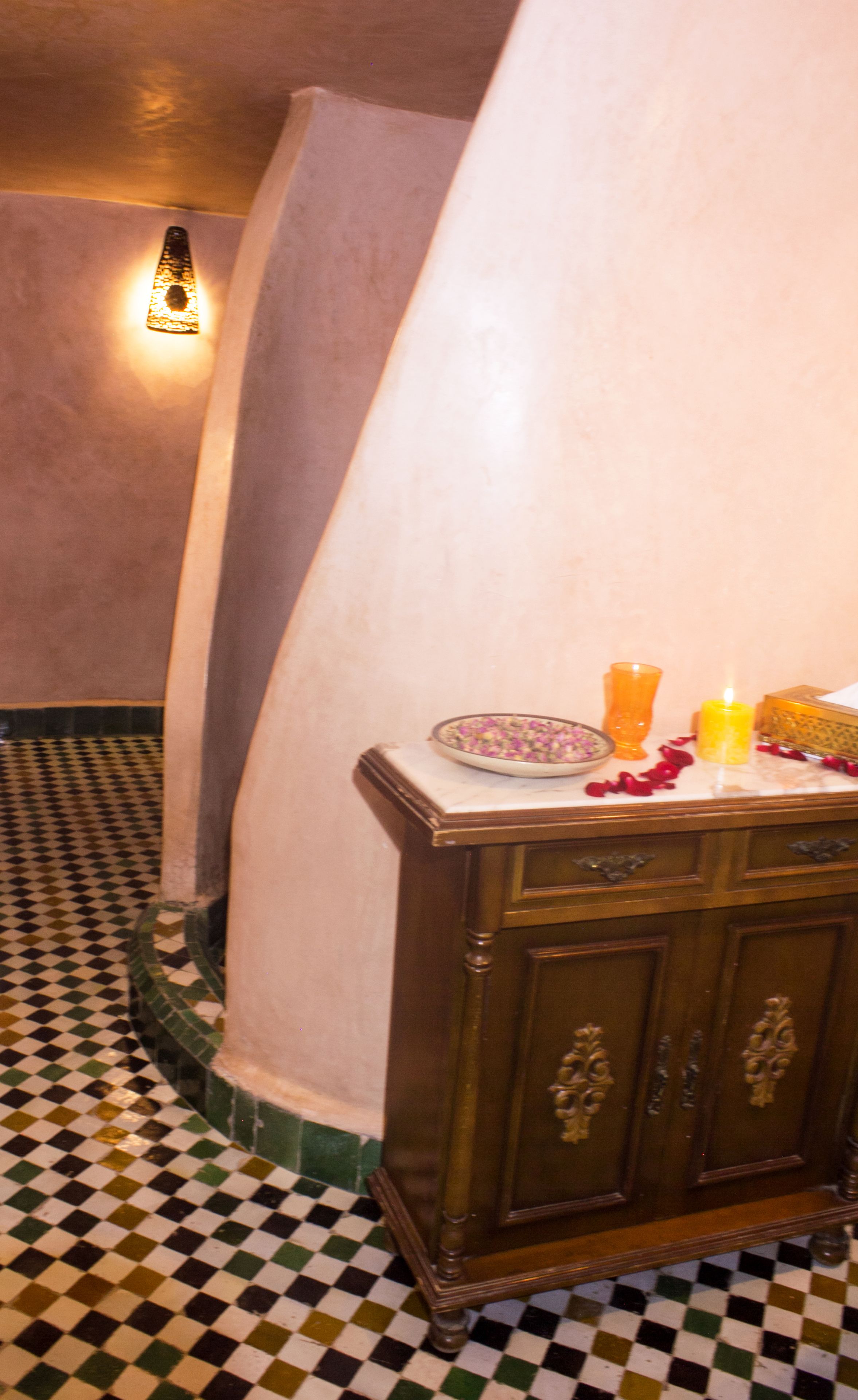 A checkered floor, a wooden cabinet, and a wall with a light fixture.