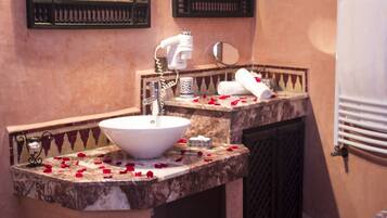 A bathroom with a marble sink, a hairdryer, a mirror, and a towel rack.
