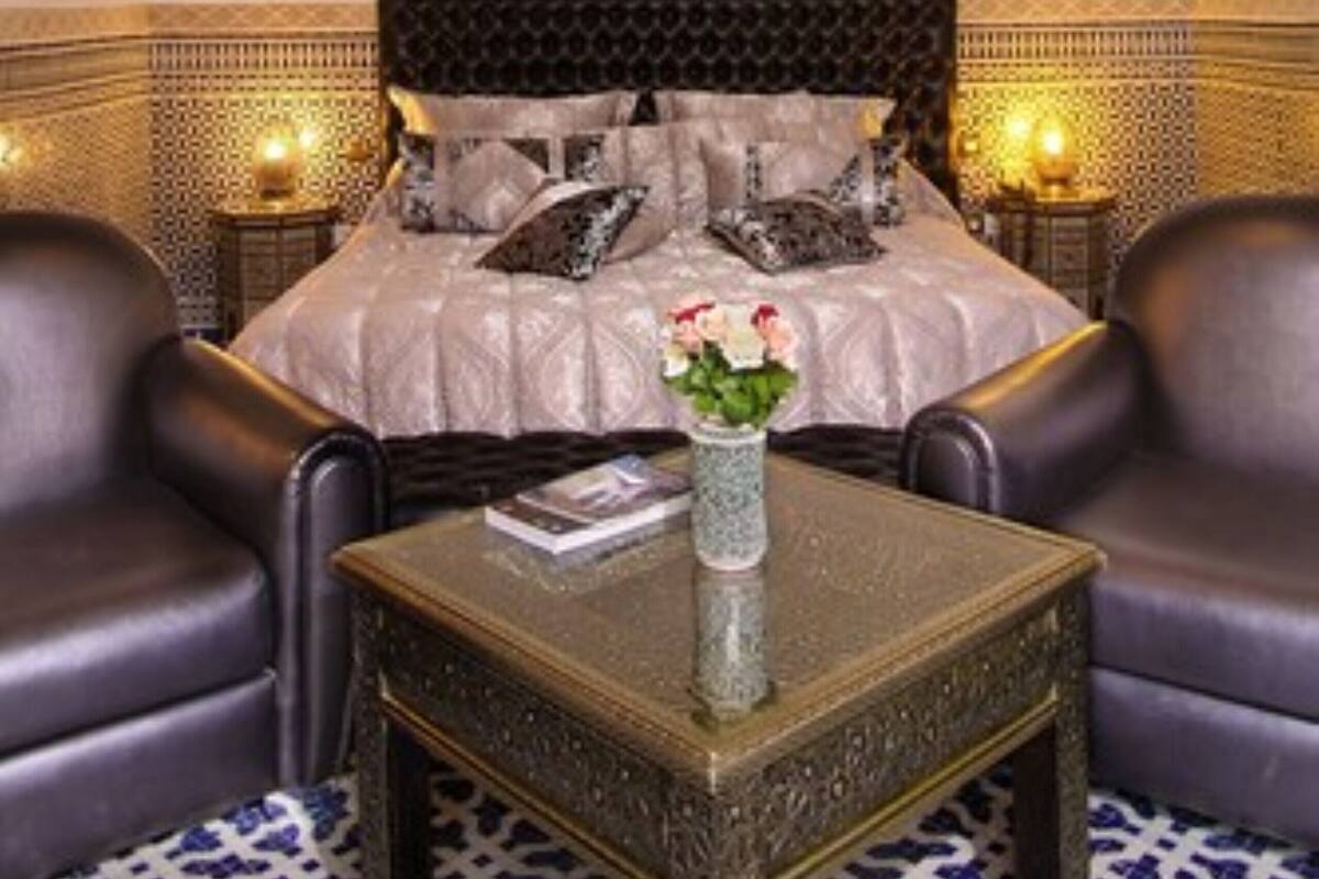 Une chambre à coucher avec un grand lit, deux tables de chevet, un vase de fleurs et un lustre.
