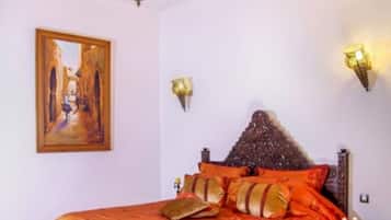 A bedroom with a large bed, a wooden headboard, and a painting on the wall.
