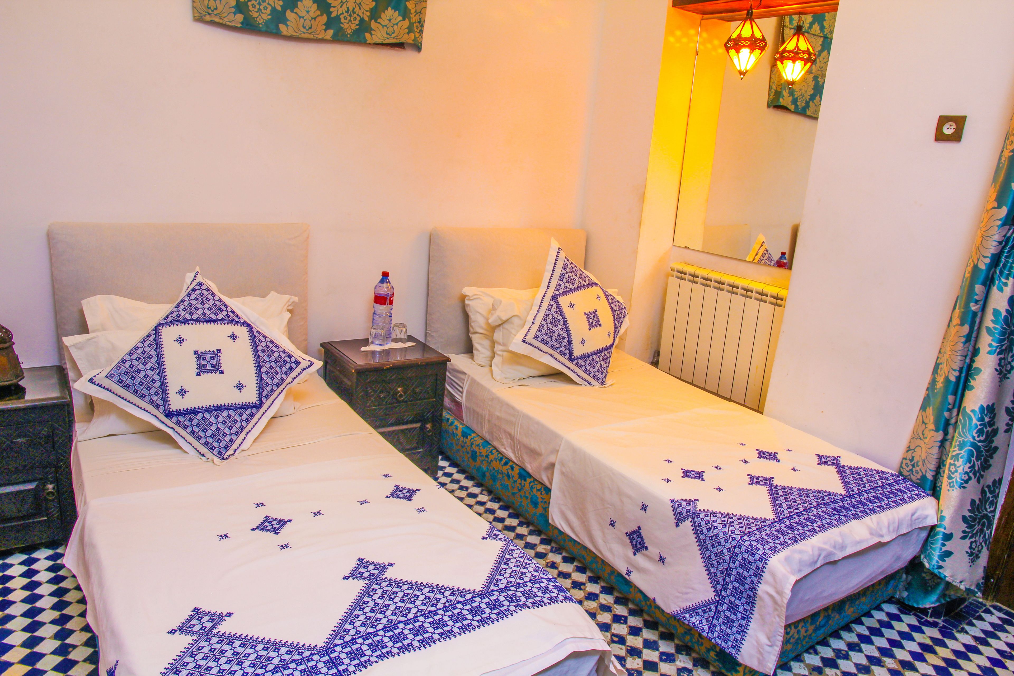 A double bed with a checkered floor, two bedside tables, and a mirror above the bed.