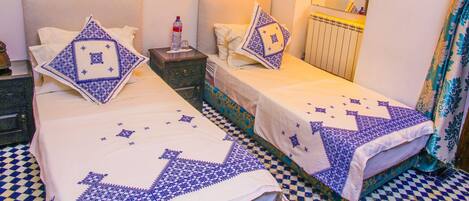 A double bed with a checkered floor, two bedside tables, and a mirror above the bed.