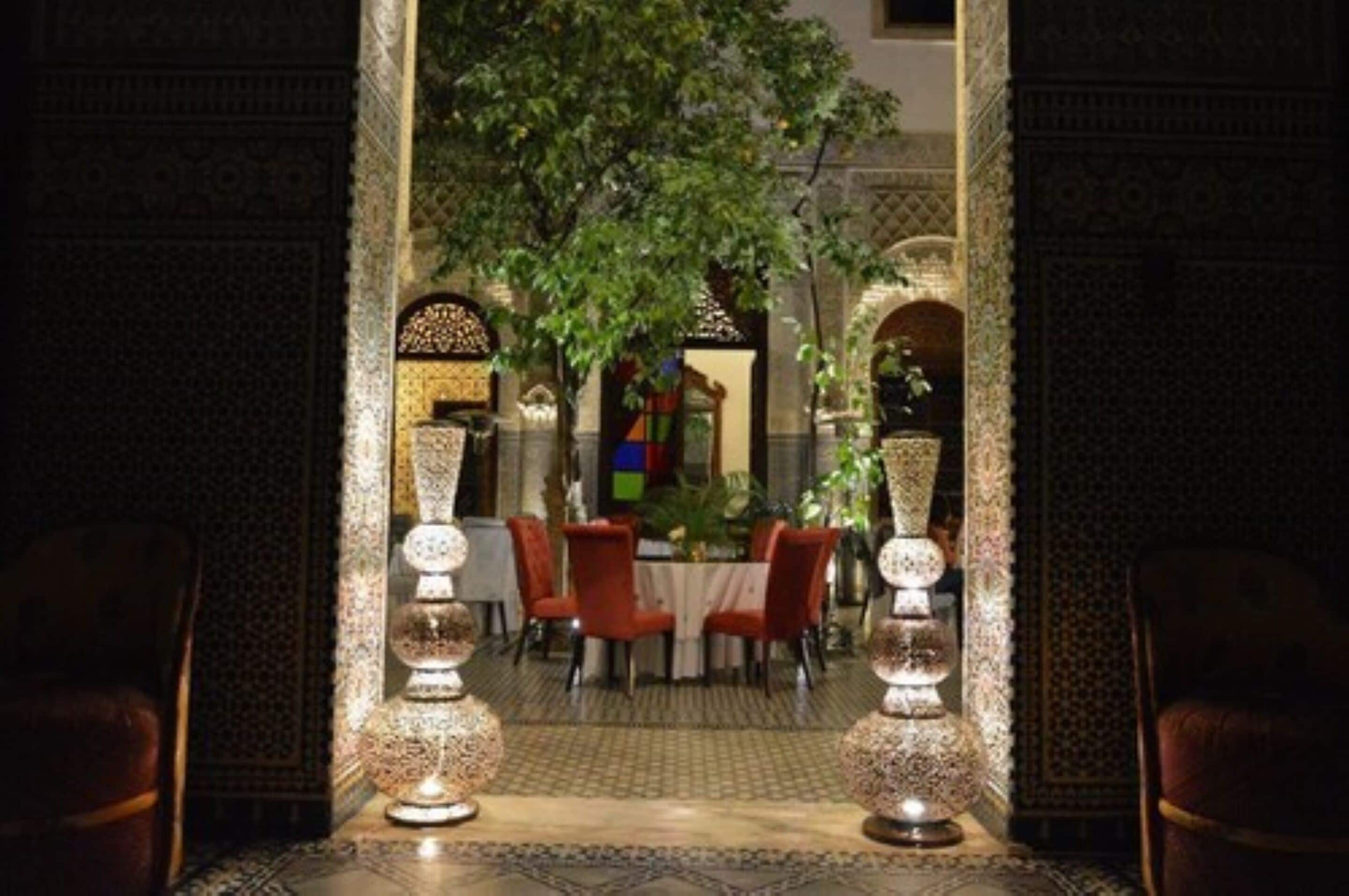 An indoor dining area with a table set for four, surrounded by ornate walls and a patterned floor.