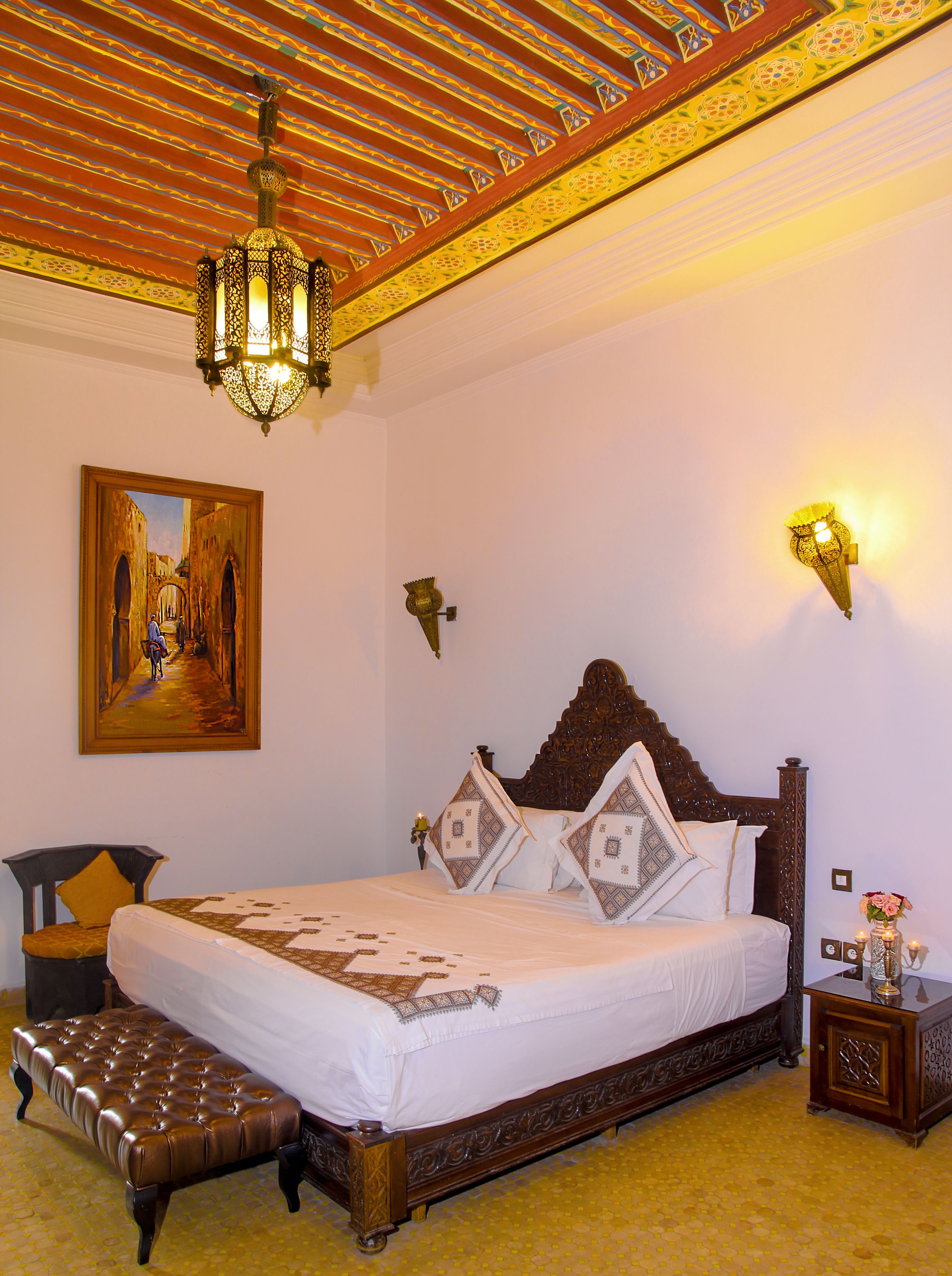 Un dormitorio con una cama grande, un techo decorado y un cuadro en la pared.