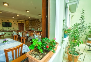 Un comedor con mesas, sillas y plantas en macetas.