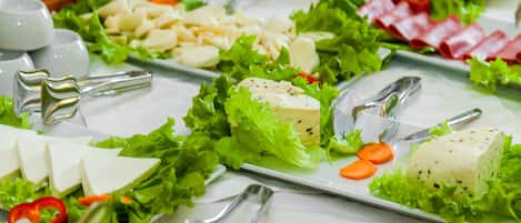 Un buffet proposant une variété de plats, notamment des fromages, des légumes et des viandes.