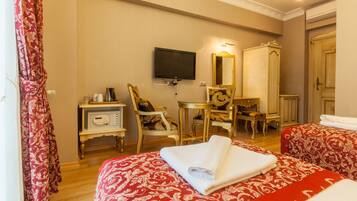 A hotel room with two beds, a TV, a desk, and a mirror.