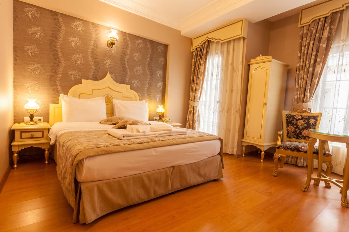 A bedroom with a large bed, a nightstand, a dresser, a chair, and a table.