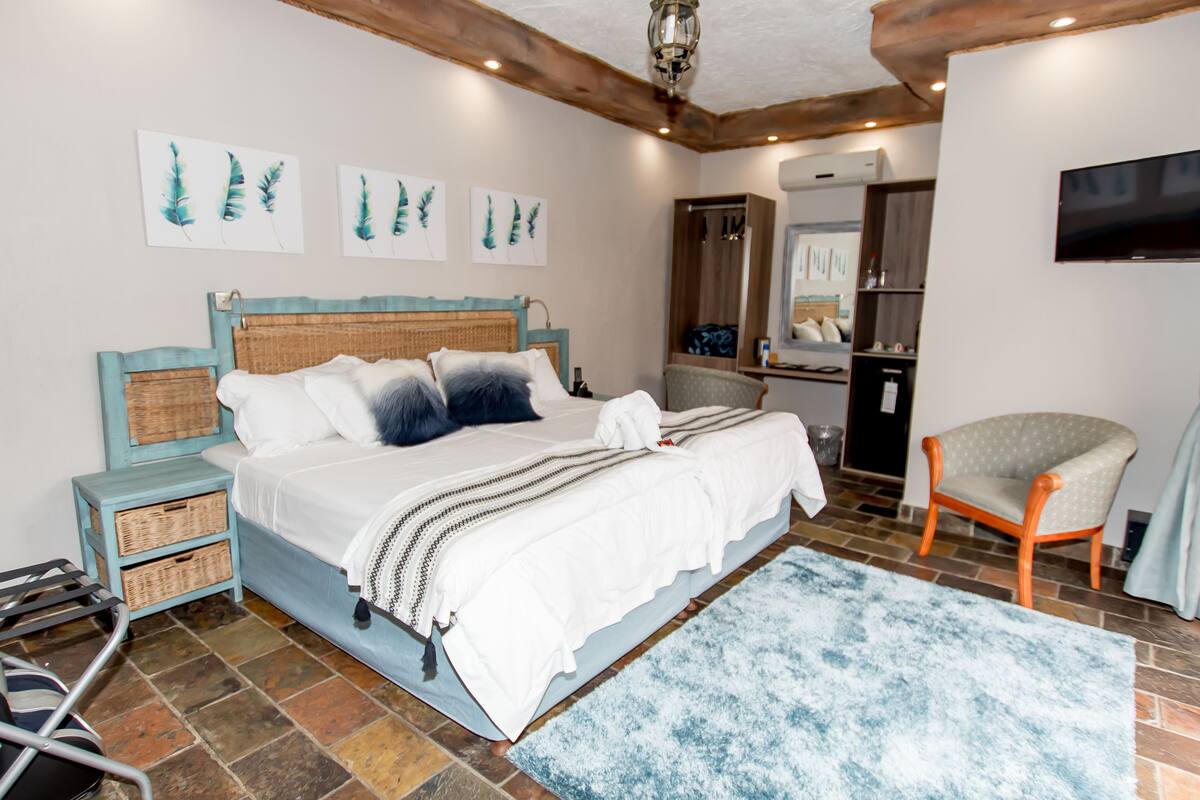 A bedroom with a bed, a chair, a TV, and artwork on the wall.