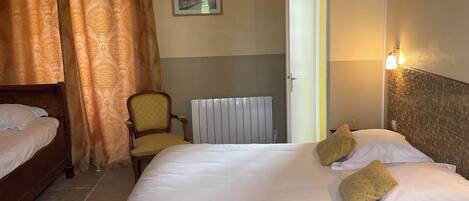 Habitación de hotel con una cama grande, una silla, un radiador y una puerta.