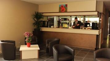 Ein Hotel-Empfangsbereich mit einer Rezeption, einer Rezeptionistin und Sitzgelegenheiten für Gäste.