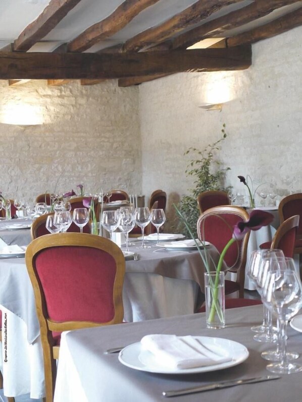 A restaurant with wooden beams, stone walls, and tables set for dining. - Domaine du Griffier (Granzay-Gript)