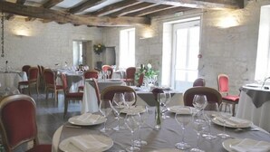 A dining area with round tables set for four, each with white tablecloths, red chairs, and wine glasses. - Domaine du Griffier (Granzay-Gript)