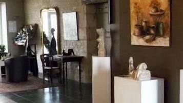 Amplia sala de estar con un ventanal, comedor con mesa y sillas, y exhibición de esculturas.