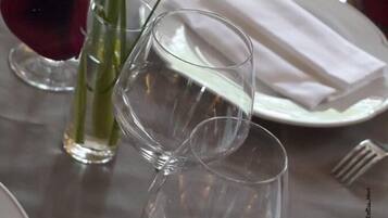 A table set with wine glasses, a vase with a flower, and a folded napkin.
