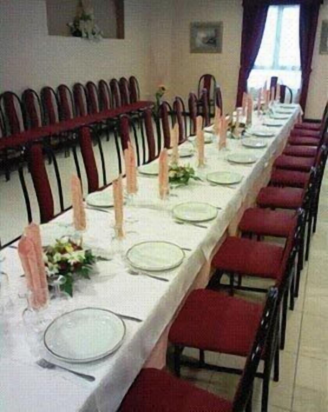 A long dining table set with plates, cutlery, and candles, surrounded by red chairs.