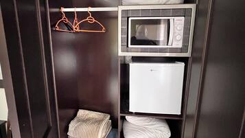 Een kast met een magnetron, een minibar en kleding.