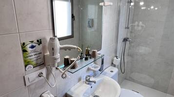 A modern bathroom with a glass shower enclosure, a pedestal sink, a toilet, and a vanity with a mirror.