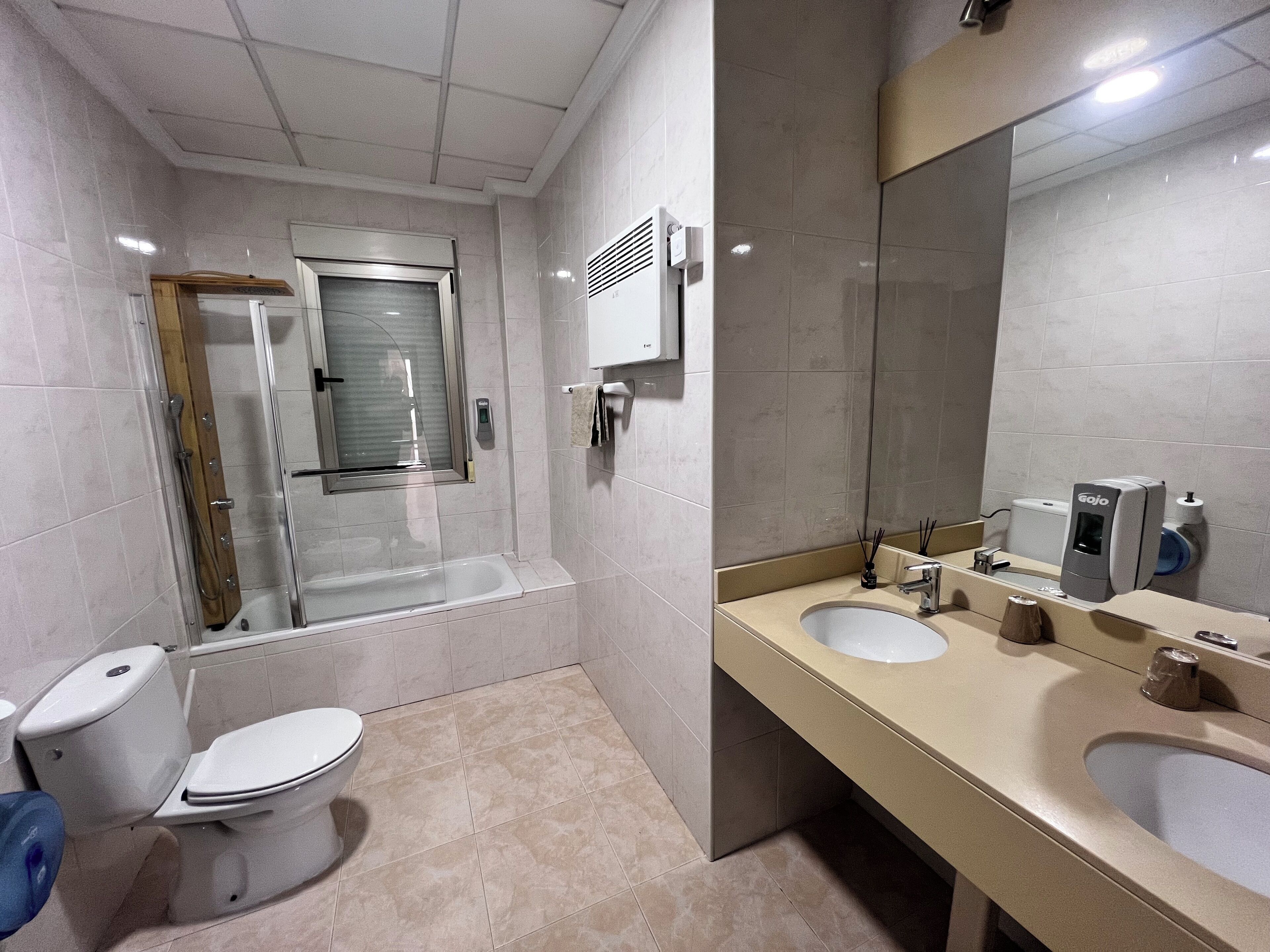 A modern bathroom with a glass-enclosed shower, a toilet, a sink, and a large mirror.