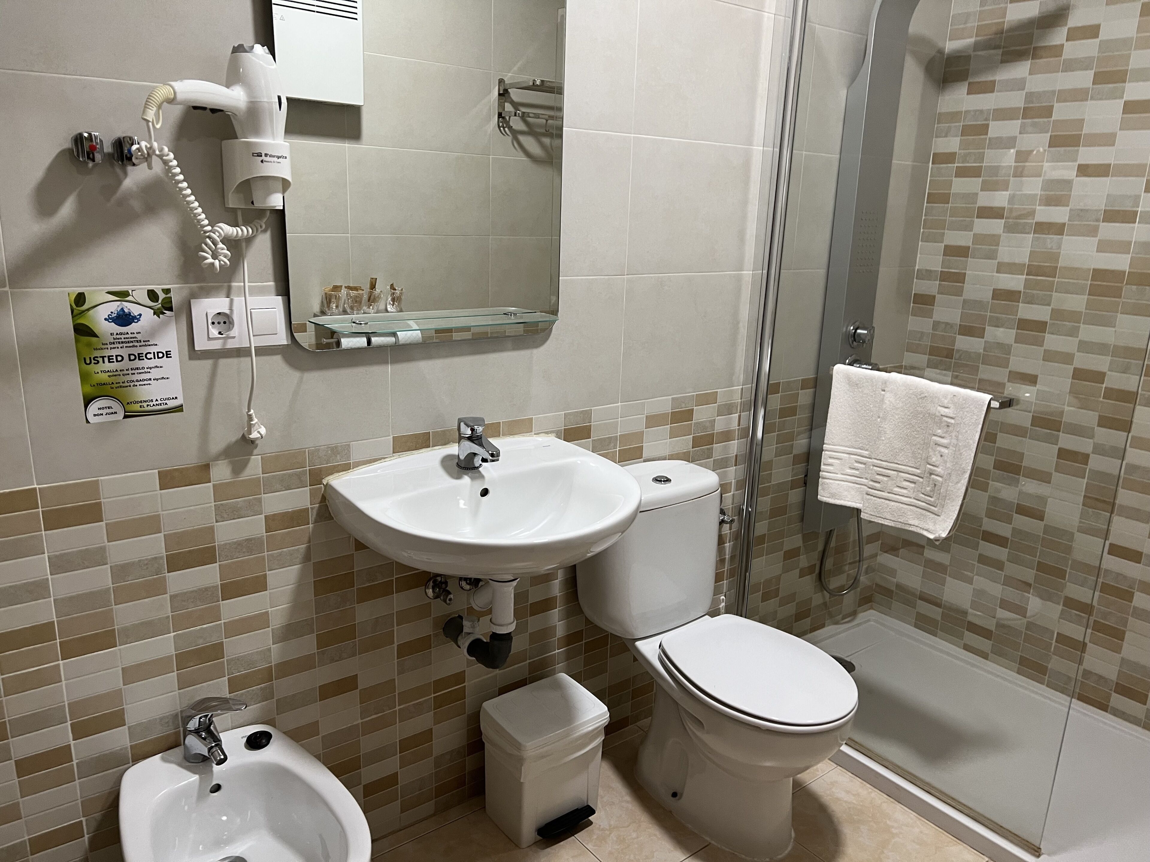 Ein Badezimmer mit Waschbecken, Toilette, Bidet und einer Duschkabine aus Glas.