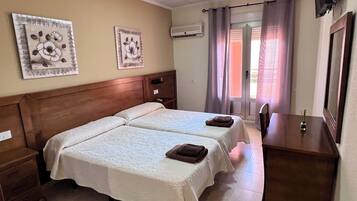 A hotel room with two beds, a wooden dresser, a TV, and artwork on the walls.