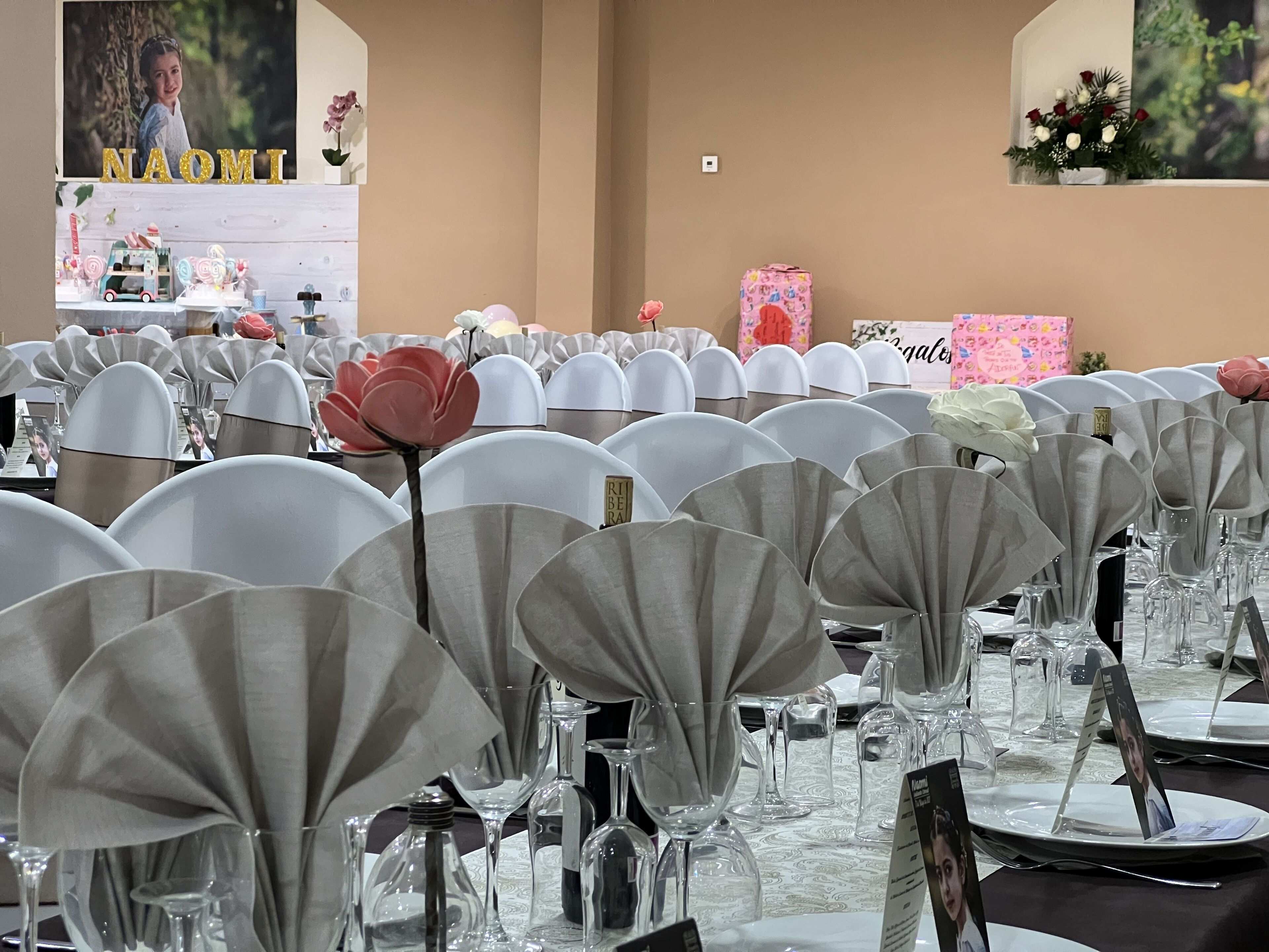 Une salle de banquet avec des tables rondes recouvertes de nappes blanches, agrémentées de couverts en argent et de verres transparents.