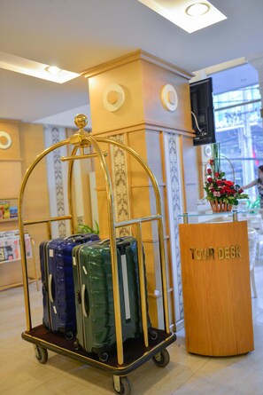 A tour desk with a cart of luggage and a floral arrangement. - Hoang Phu Gia (Ho Chi Minh City)