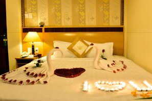 A hotel room with a neatly made bed, a bedside lamp, a phone, and decorative floral arrangements. - Hoang Phu Gia (Ho Chi Minh City)