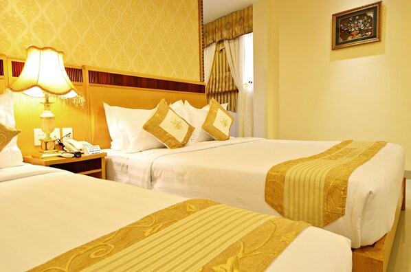 A hotel room with two beds, a nightstand with a lamp, a telephone, and a framed picture on the wall. - Hoang Phu Gia (Ho Chi Minh City)