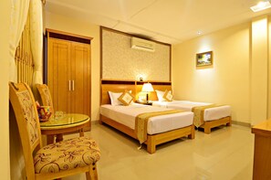 A hotel room with two beds, a wooden wardrobe, a glass table with chairs, and a wall-mounted air conditioner. - Hoang Phu Gia (Ho Chi Minh City)