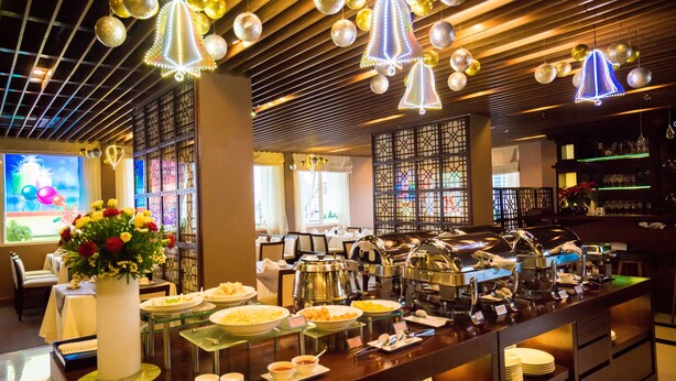 Un espace buffet avec différents stands de nourriture, un vase décoratif rempli de fleurs et un bar avec une vitrine.