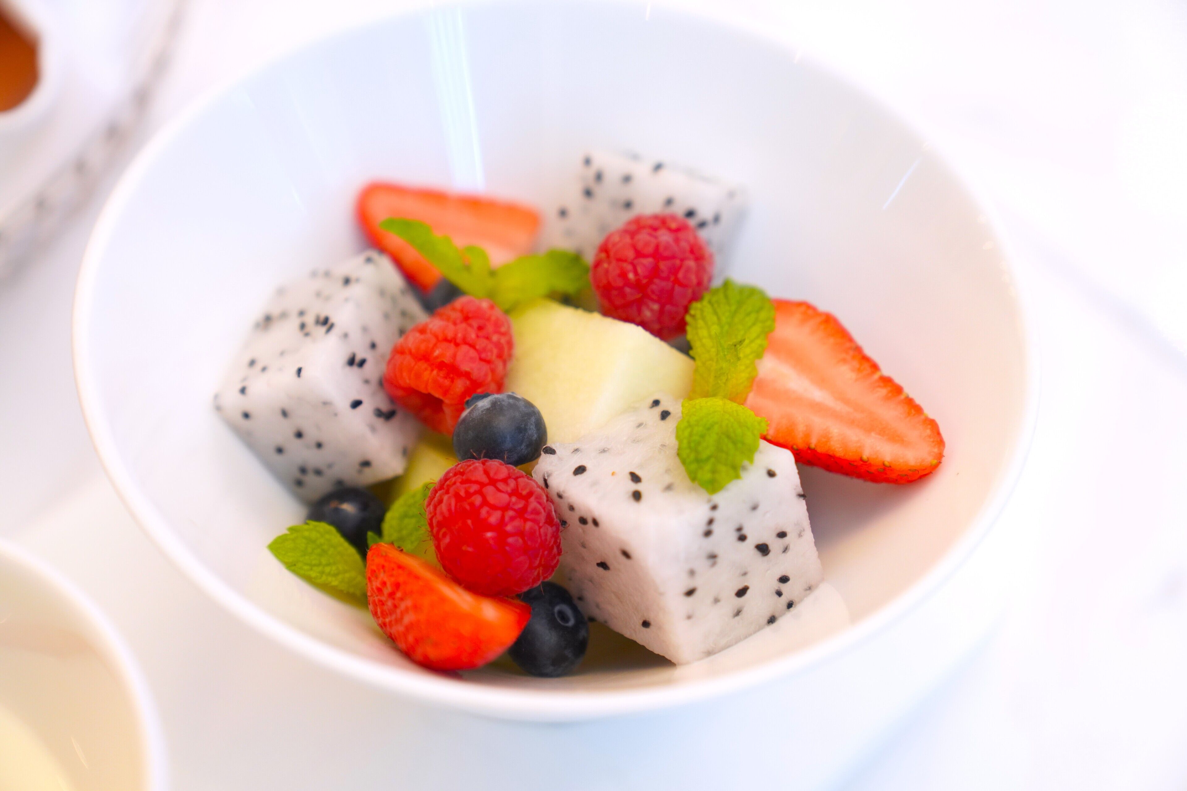 Eine Schüssel Obstsalat mit Erdbeeren, Blaubeeren, Himbeeren und Drachenfrucht.