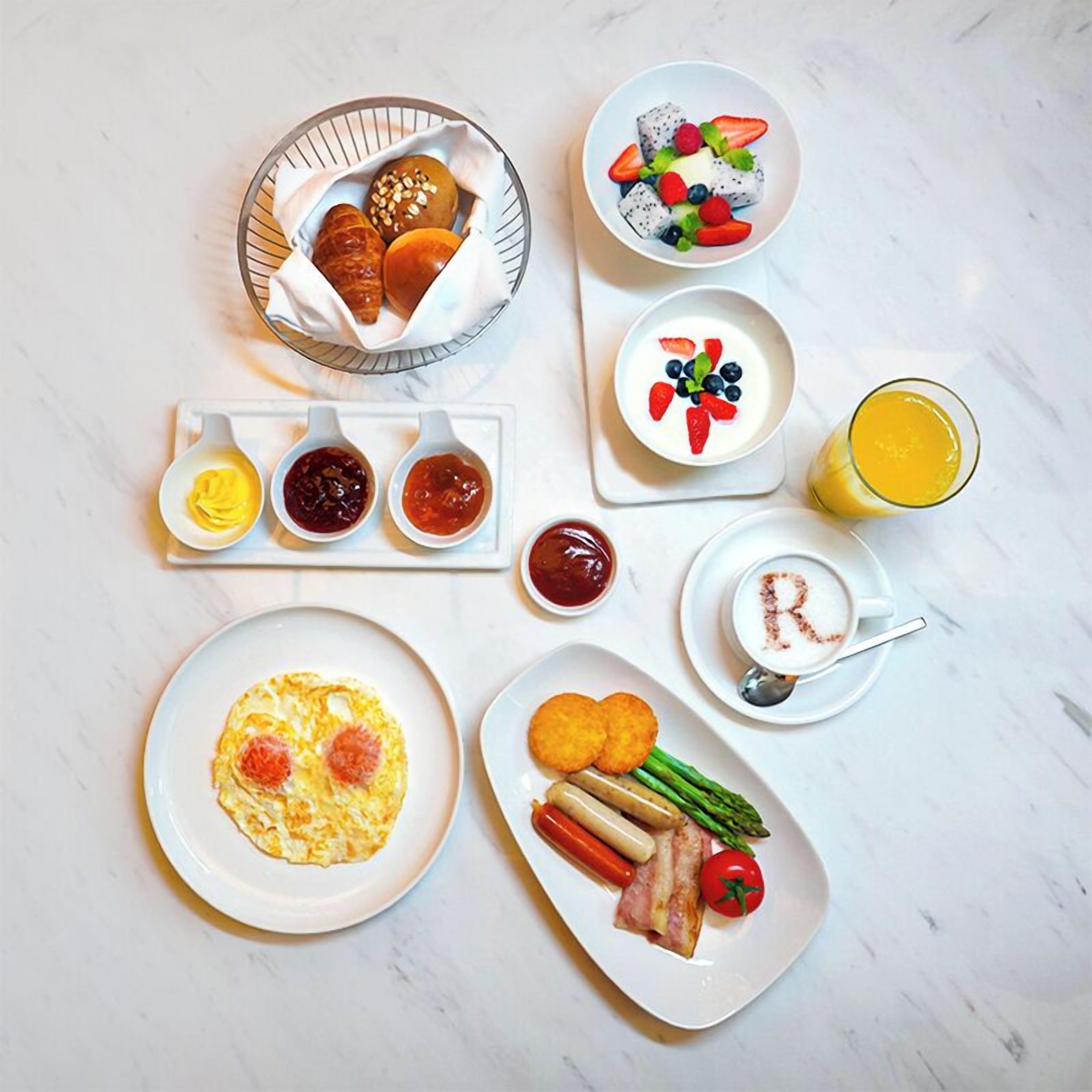 A breakfast spread with various dishes including eggs, sausages, and fruits.