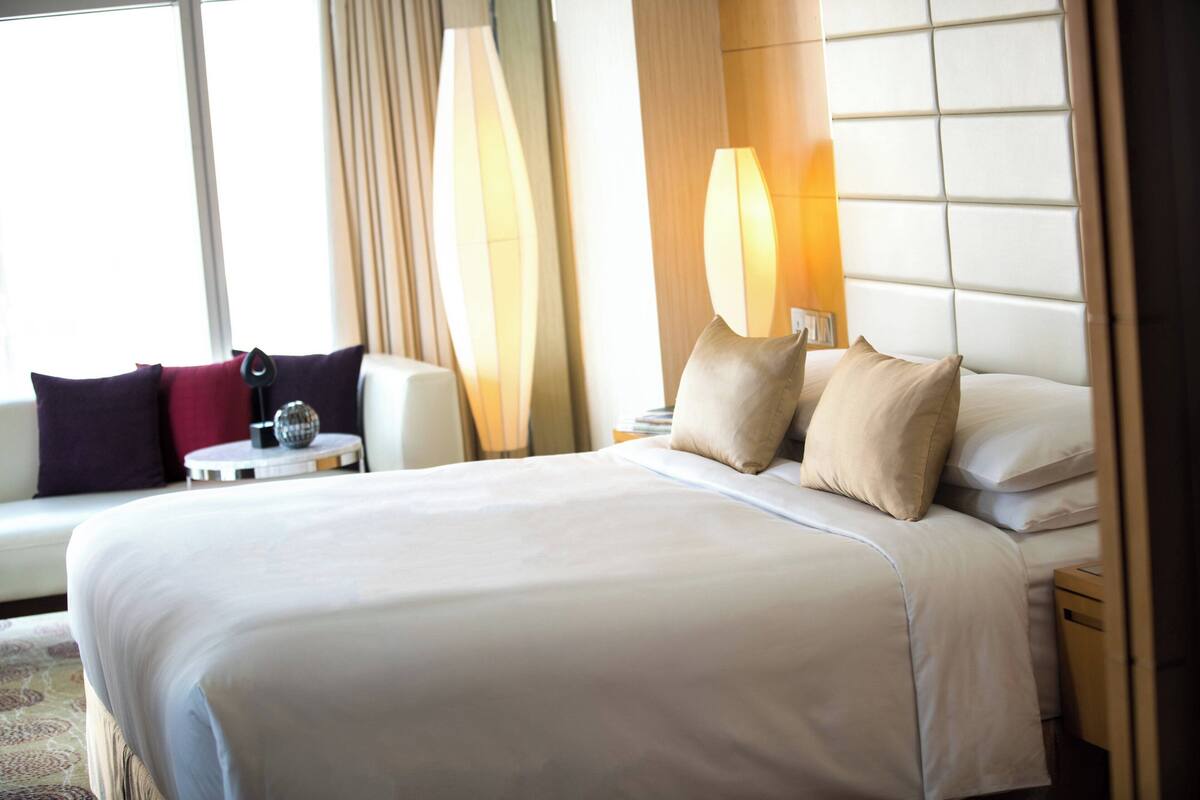 A hotel room with a large bed, a sofa, a small table, and a nightstand.