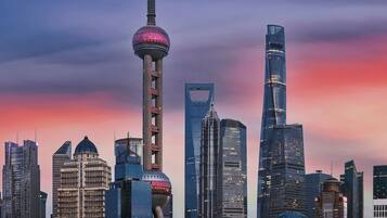A city skyline with modern skyscrapers, a prominent tower with a spherical observation deck, and a body of water in the foreground.
