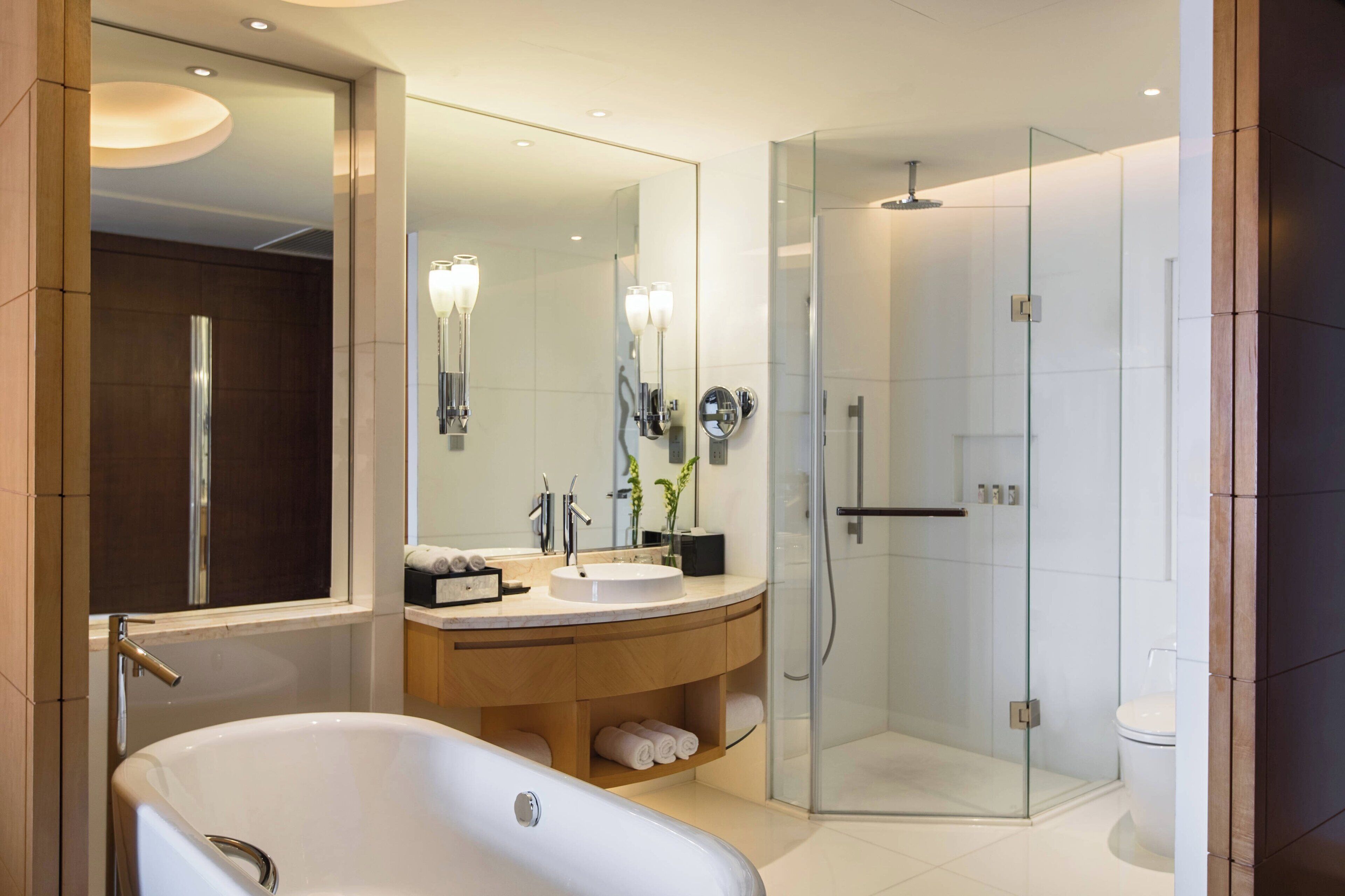 A modern bathroom with a freestanding bathtub, a glass-enclosed shower, and a large mirror.