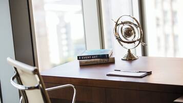 Een houten bureau met een metalen stoel, een metalen sculptuur en een stapel boeken.