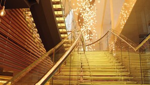 Una escalera con barandilla de vidrio y lámparas colgantes.