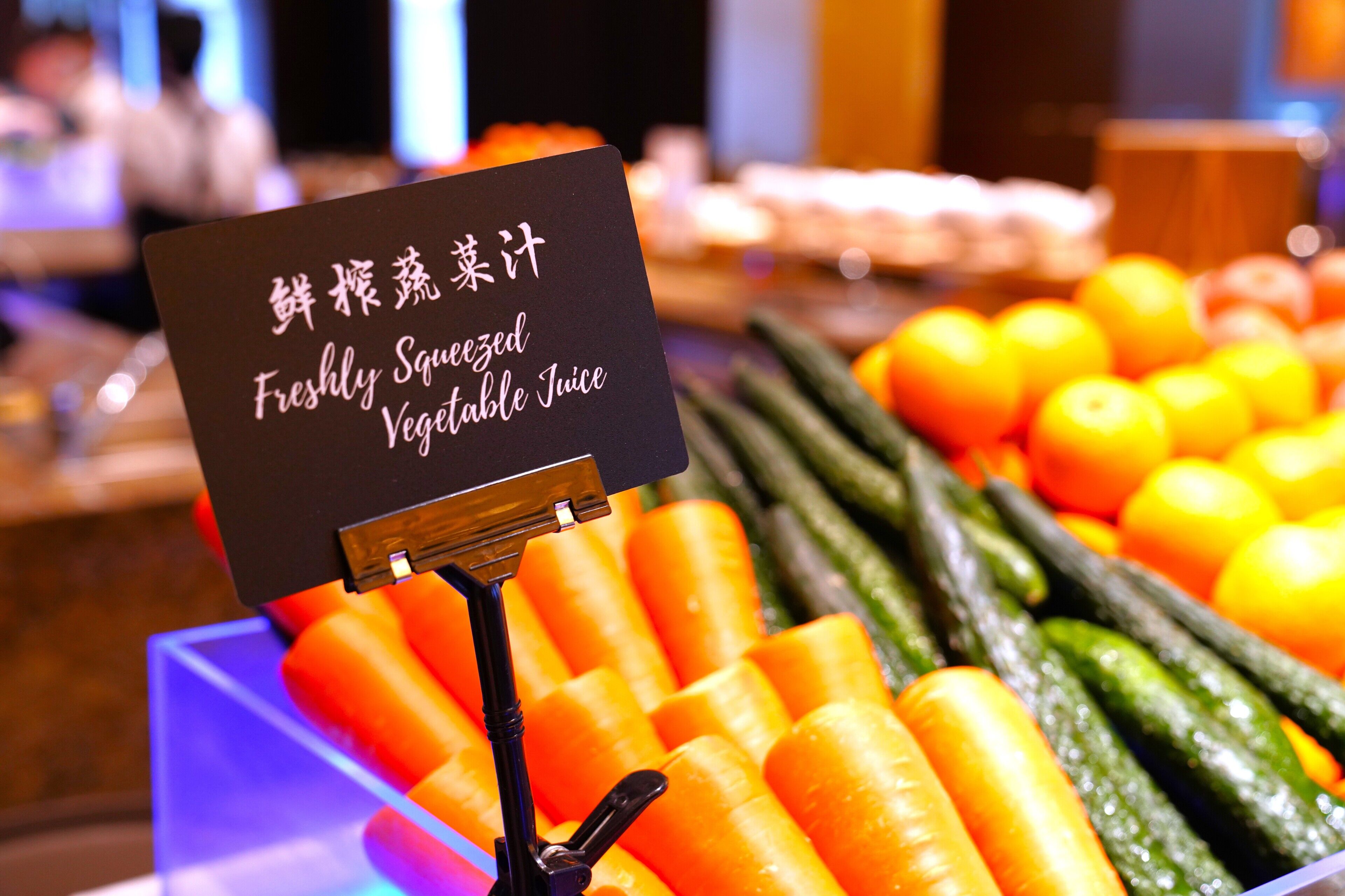 A display of fresh vegetables and a sign indicating 'Freshly Squeezed Vegetable Juice.'