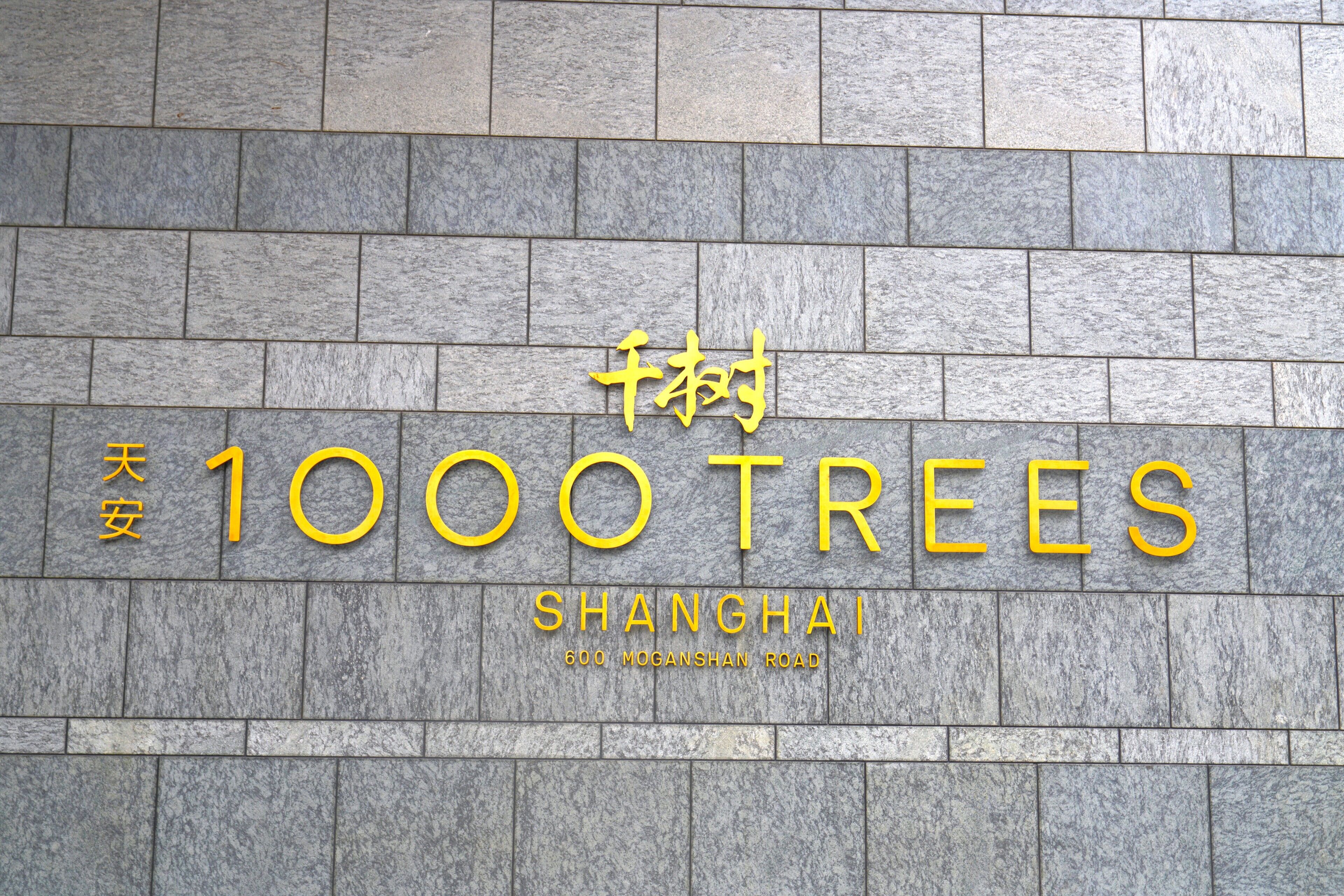 Fachada de edificio con el nombre '1000 Trees' e indicación de la ubicación: 'Shanghái'.